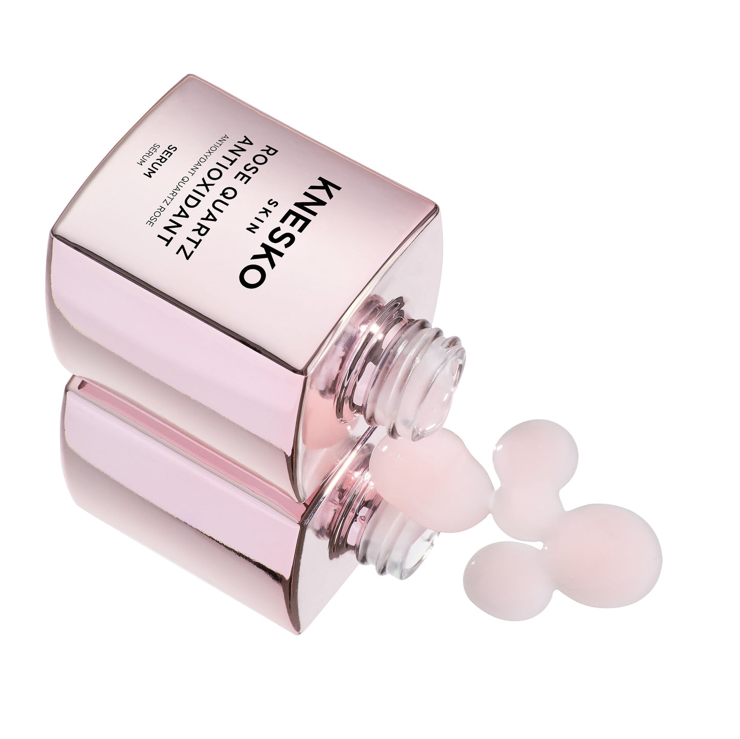 pink serum bottle that says knesko skin rose quartz antioxidant serum dripping onto the table.